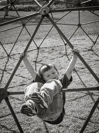 Full length of playful boy on jungle gym at playground