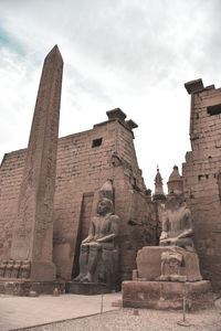 Low angle view of statue of historic building against sky