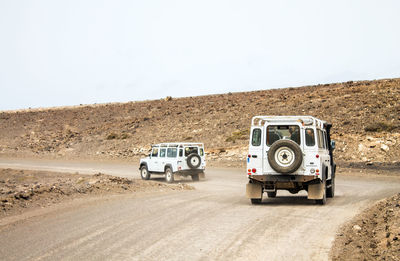 Vintage car on desert land against clear sky