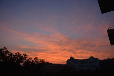 Silhouette trees against orange sky