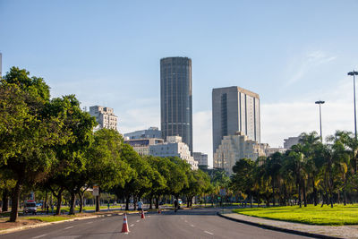 Road amidst trees and buildings against sky