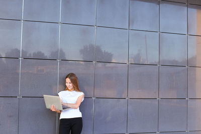 Young woman standing against wall