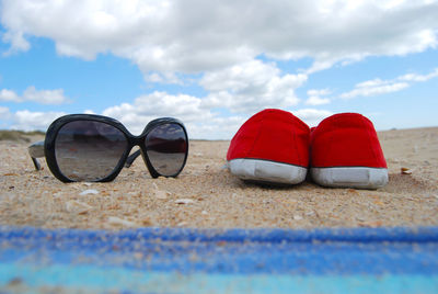 Close-up of sunglasses on beach against sky