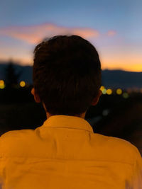 Rear view of boy against sky during sunset
