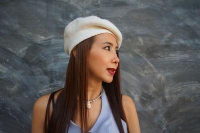 Woman looking away against wall