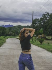 Woman standing by road against sky