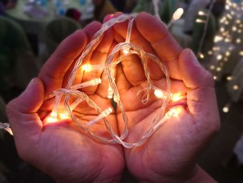 Cropped hands holding illuminated string lights