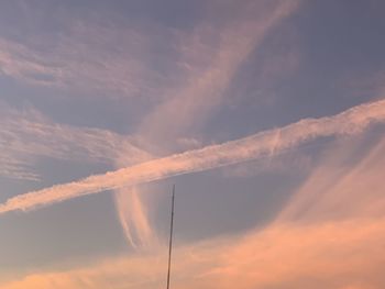 Low angle view of vapor trails in sky during sunset