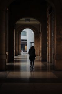 Rear view of man walking in corridor of building