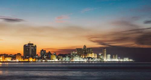 Illuminated buildings in city at sunset