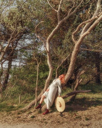 Rear view of woman sitting on tree