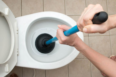 Low section of person cleaning toilet bowl in bathroom