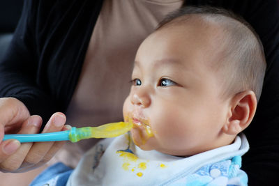 Midsection of mother feeding baby at home