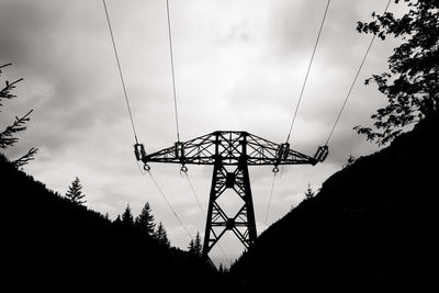 Low angle view of silhouette electricity pylon against sky