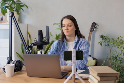 Young woman using laptop while sitting on sofa at home