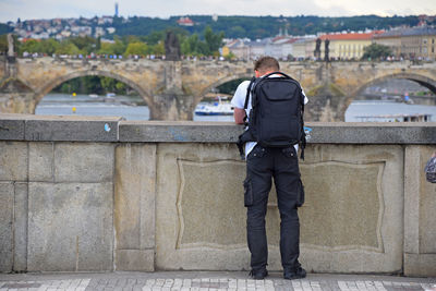 Rear view of man with backpack looking at charles bridge