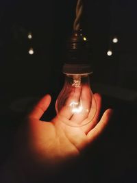 Close-up of hand holding illuminated light bulb