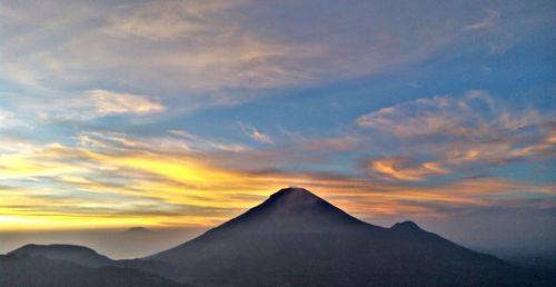 Scenic view of mountain against cloudy sky during sunset