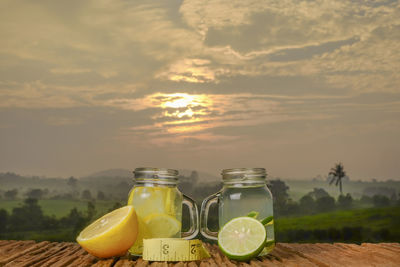 Glass of jar on table against sky during sunset