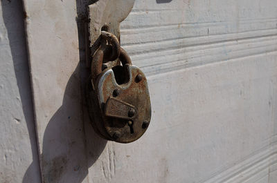 Close-up of rusty padlock hanging on closed door