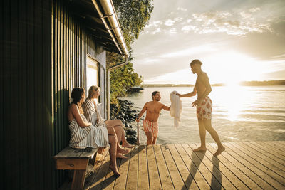 Young friends enjoying vacation at jetty during sunset