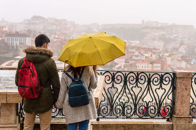 Rear view of people standing by railing in rain