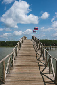 Wooden pier over lake against sky