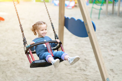 Full length of girl enjoying on swing at playground