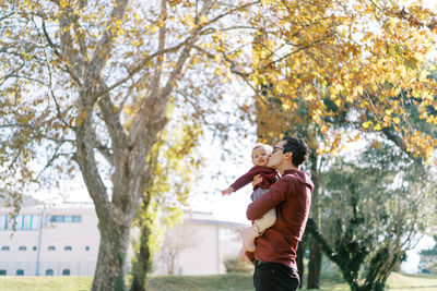 Low angle view of young woman standing against trees