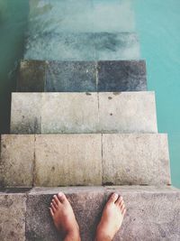 Low section of woman on steps at poolside