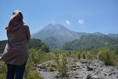 Rear view of woman looking at mountains against sky