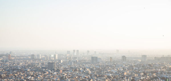 Aerial view of buildings in city against clear sky