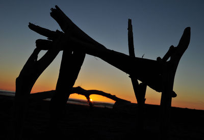 Silhouette built structure on beach against clear sky during sunset