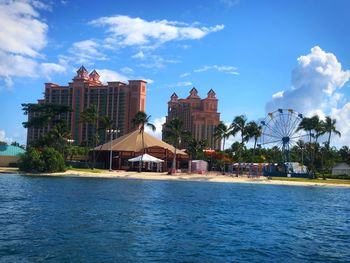 Buildings at waterfront against cloudy sky