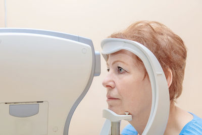 An adult woman at an ophthalmologist's appointment checks her vision on a special apparatus. 