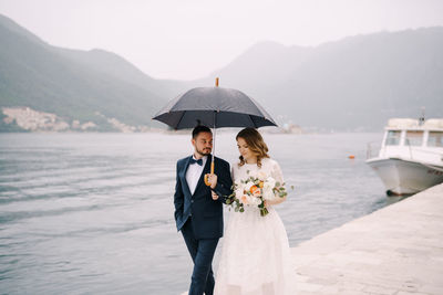 Rear view of woman holding umbrella while standing against sky