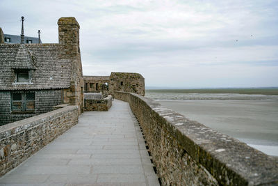 View of castle on beach against cloudy sky