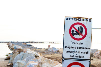 Information sign on beach against clear sky