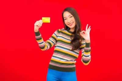 Portrait of a smiling young woman against red background