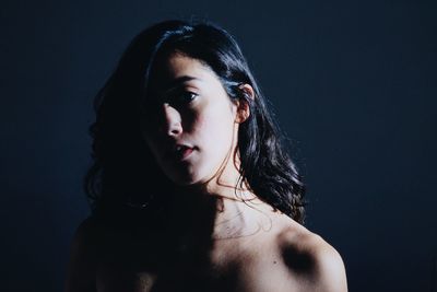 Close-up portrait of young woman against gray background