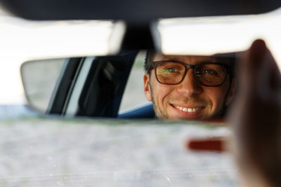 Close-up of smiling man looking in rear-view mirror