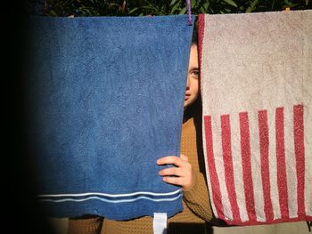 Portrait of young woman hiding behind towels