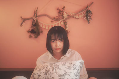 Portrait of a girl sitting against orange wall