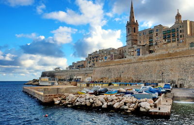 Boats moored by and buildings against sky