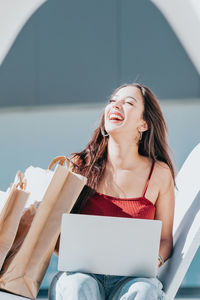 Happy woman with laptop and shopping bag