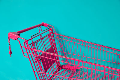 Pink shopping cart against colored background