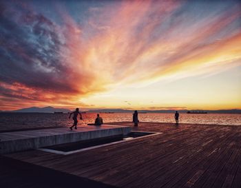 People on beach against sky during sunset