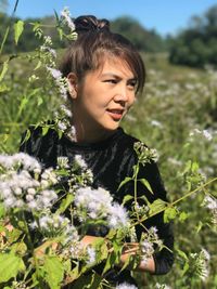 Young woman standing against flowers