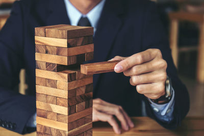 Close-up midsection businessman stacking wooden blocks on table