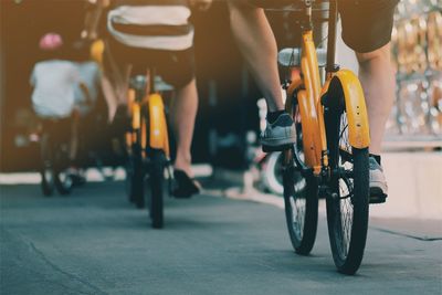 Low section of people with bicycle on road